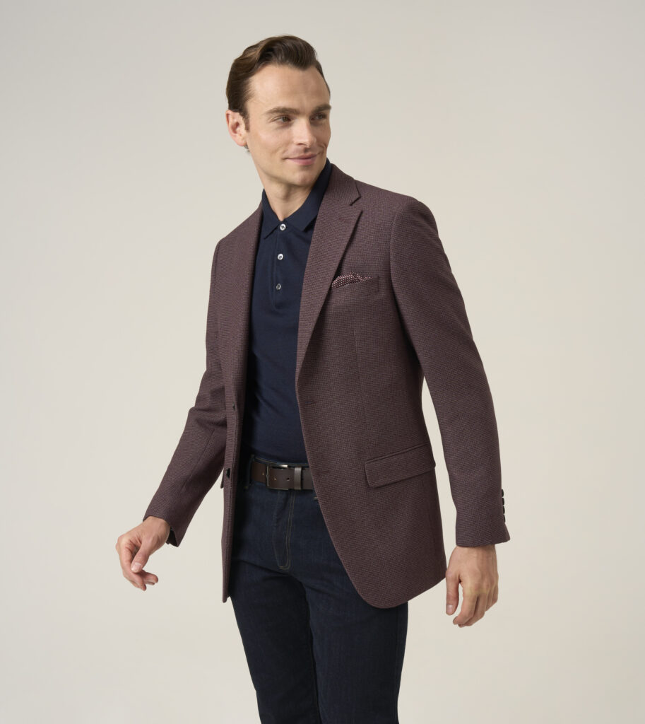 Man is wearing berry purple double-breasted jacket with woolen navy polo shirt, dark jeans and brown belt.